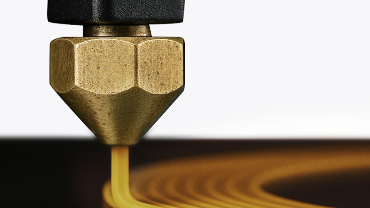 A close-up view of an FDM 3D printer nozzle extruding melted plastic filament to illustrate how fused deposition modeling works.