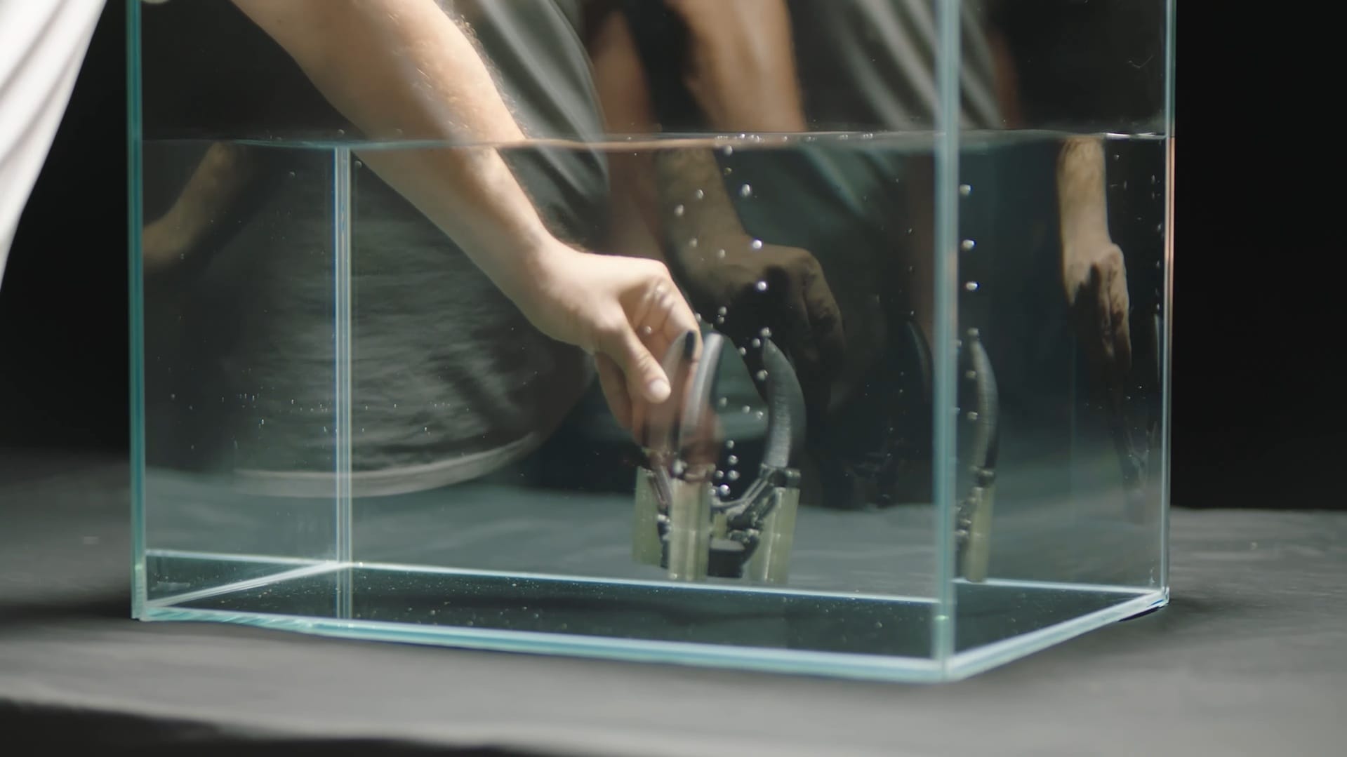 A complex mechanical 3D print submerged in water as its white PVA support structures dissolve, illustrating how soluble filaments enable the creation of steep overhangs and intricate geometries.